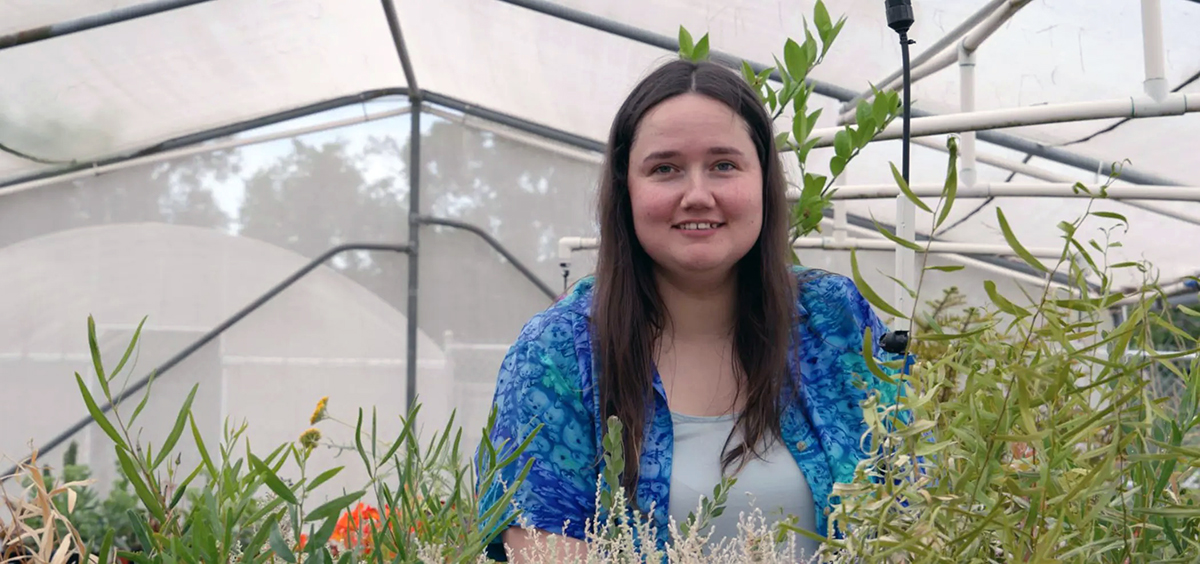 Woman in a greenhouse surrounded by plants.